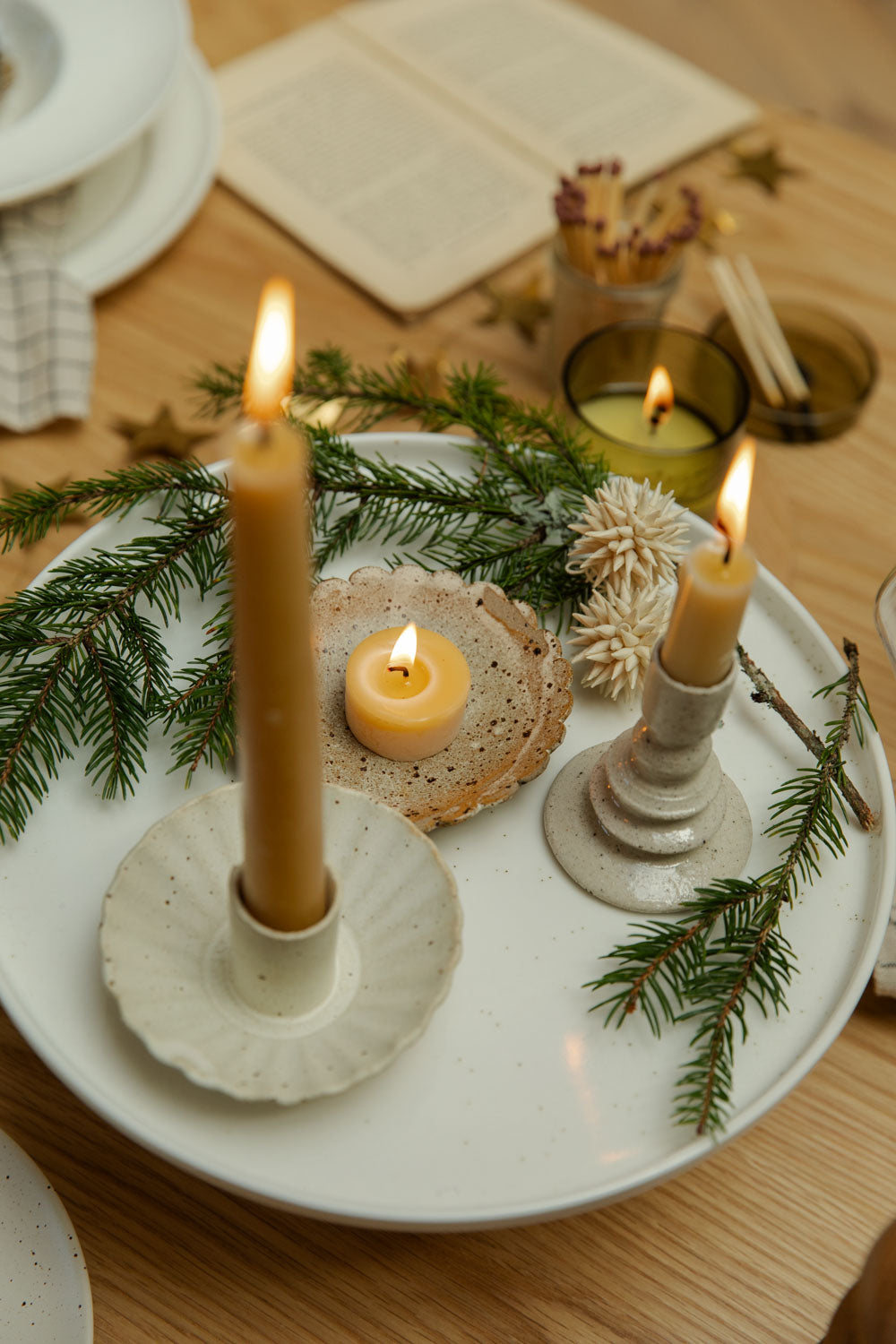 Decorative table setting with candles, greenery, and bread on a white plate.