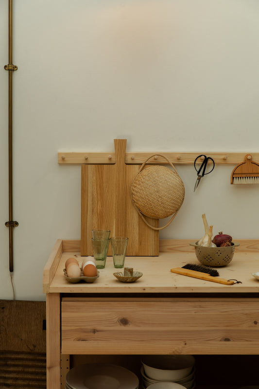 Wooden kitchen worktop with wooden chopping board, glasses, eggs and other kitchenalia.
