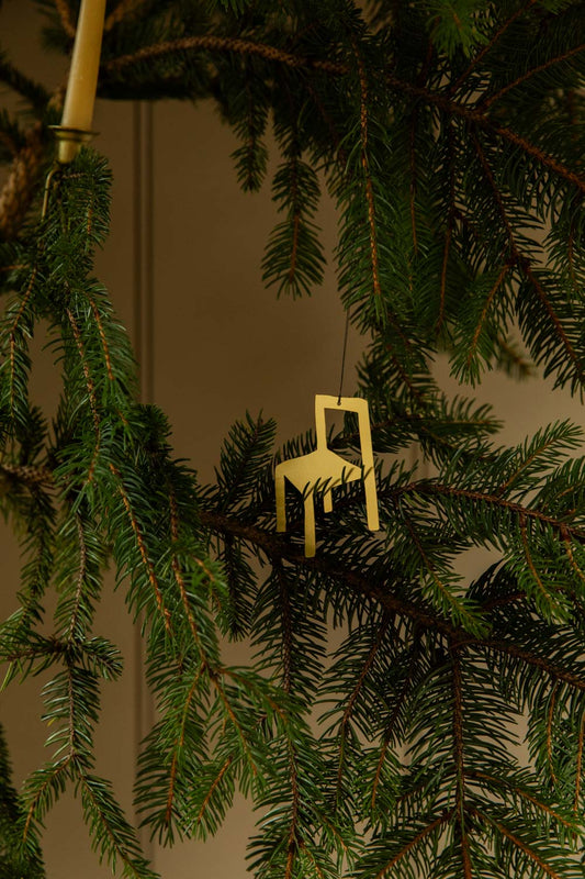 Small gold coloured metal chair ornament on a Christmas tree branch