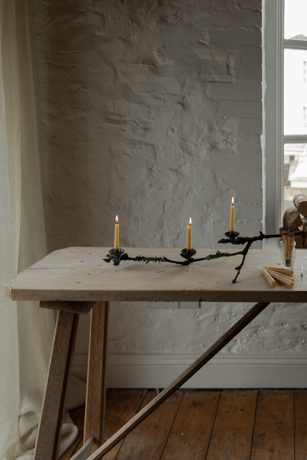 Wooden table with a decorative candle holder against a textured wall.