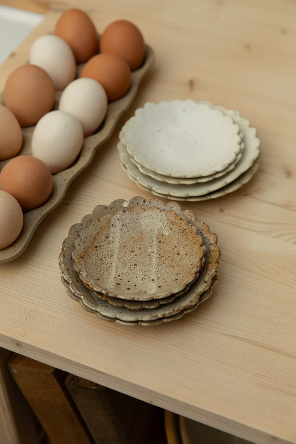 Stacked ceramic plates on a wooden surface with eggs in the background