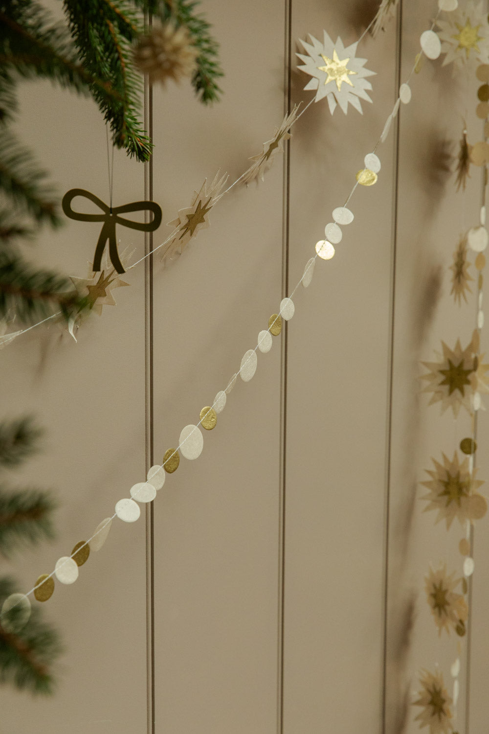 Decorative paper garland with fir branch and a bow decoration against a wooden surface