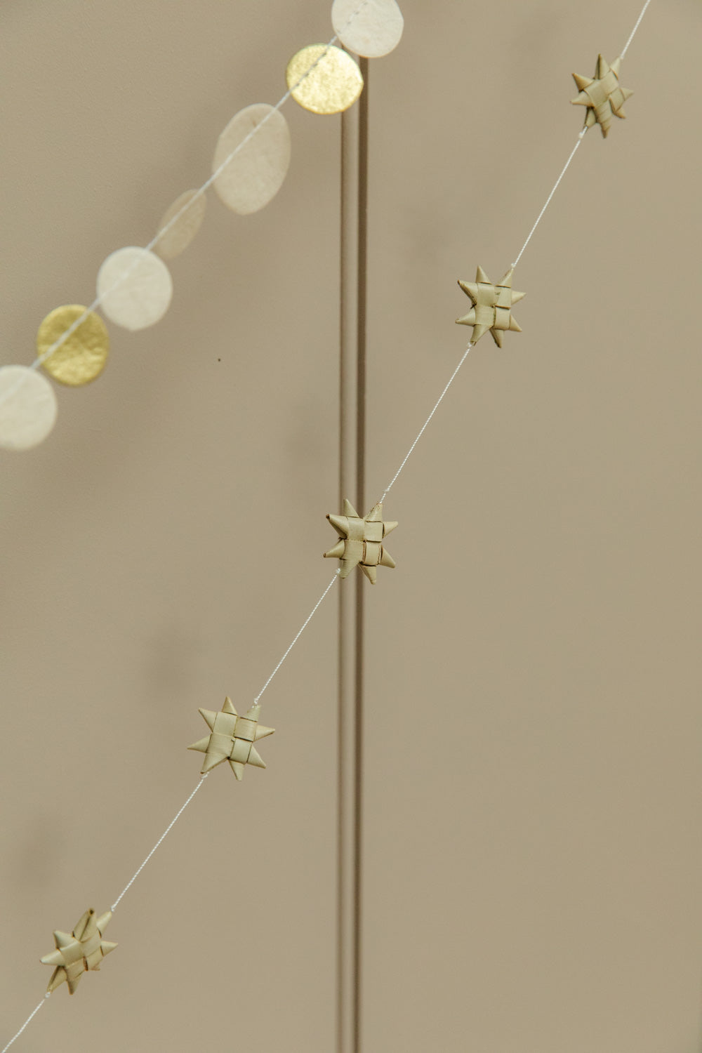 Decorative string with gold stars and circular garland on a beige background