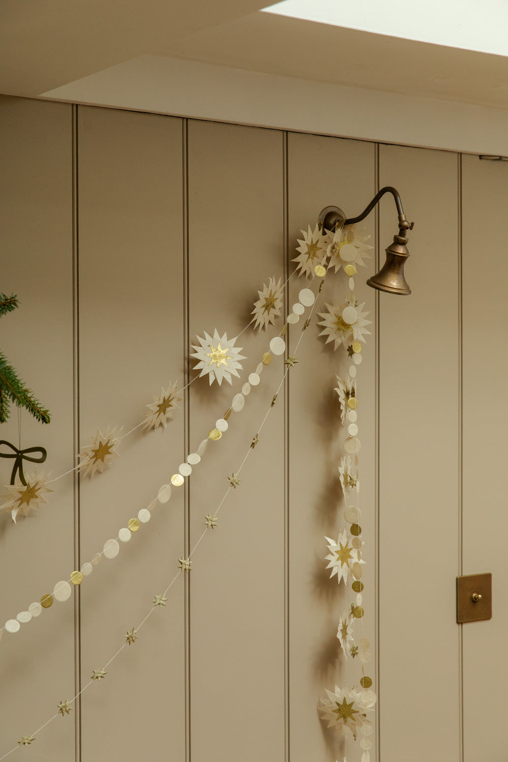 Decorative paper garlands with fir branch and a bow decoration against a wooden surface