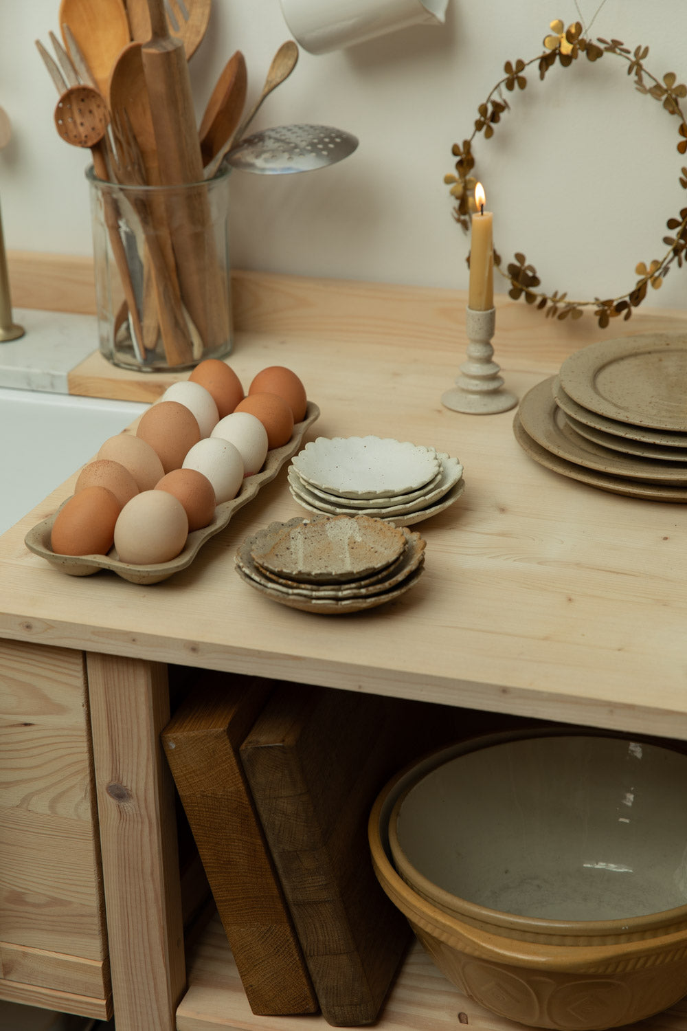 Kitchen counter with wooden utensils, eggs, and ceramic plates.