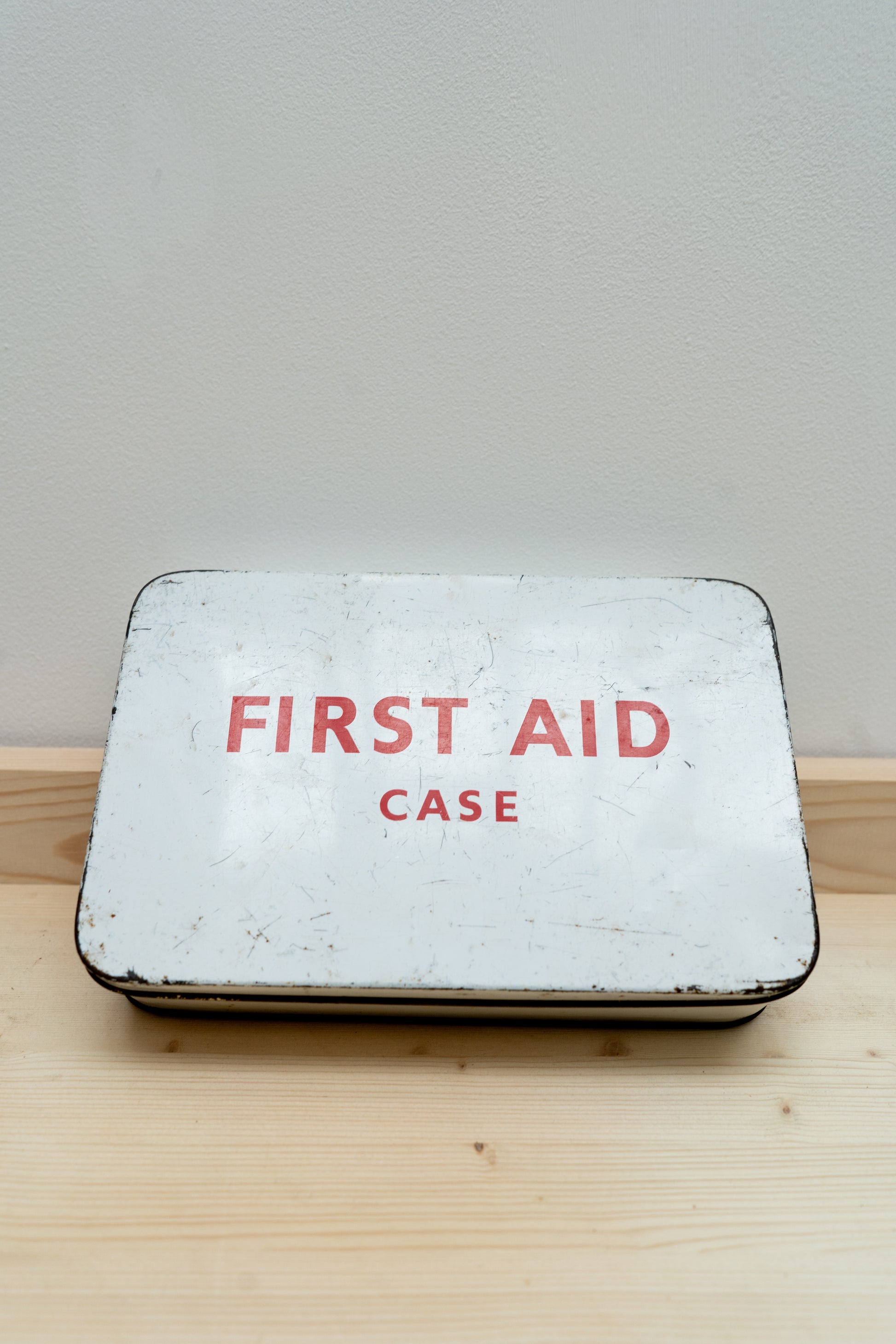 Vintage-style first aid case with 'FIRST AID CASE' text on a wooden surface.