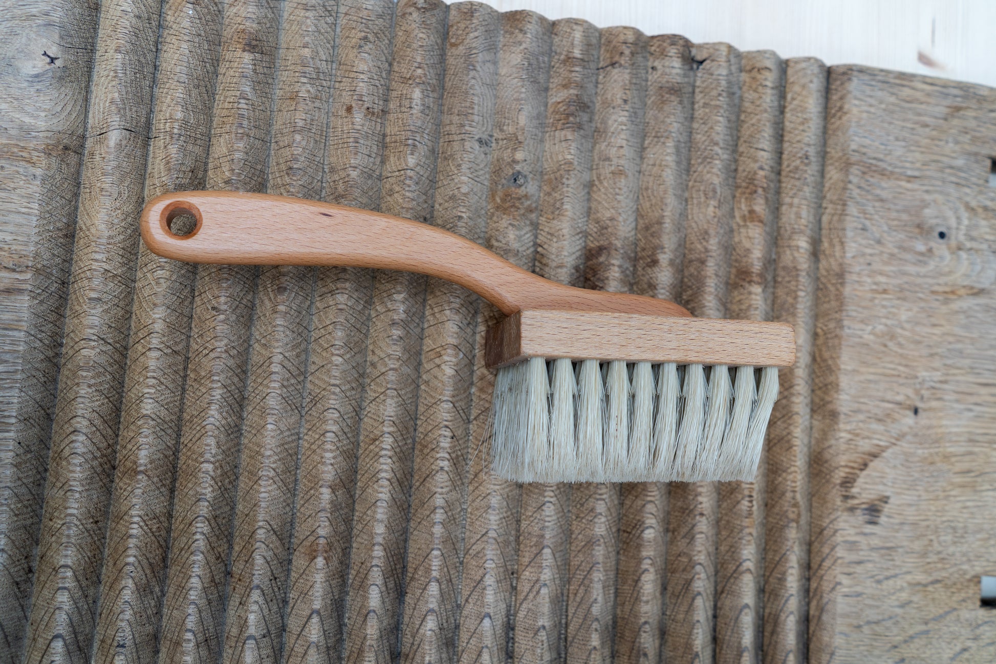 Wooden brush with a handle on a textured wooden surface