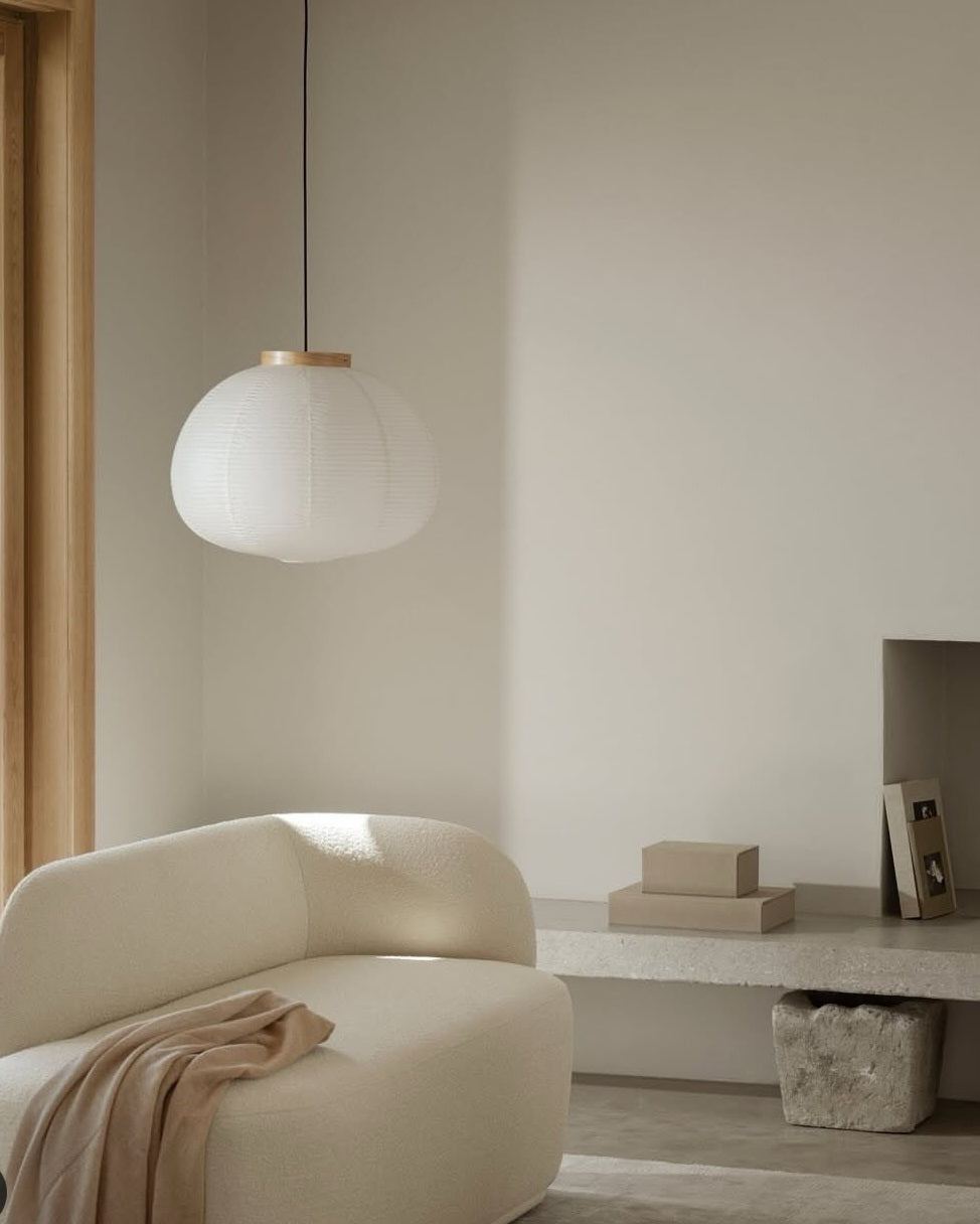Modern interior with a white pendant light, beige sofa, and minimal decor.