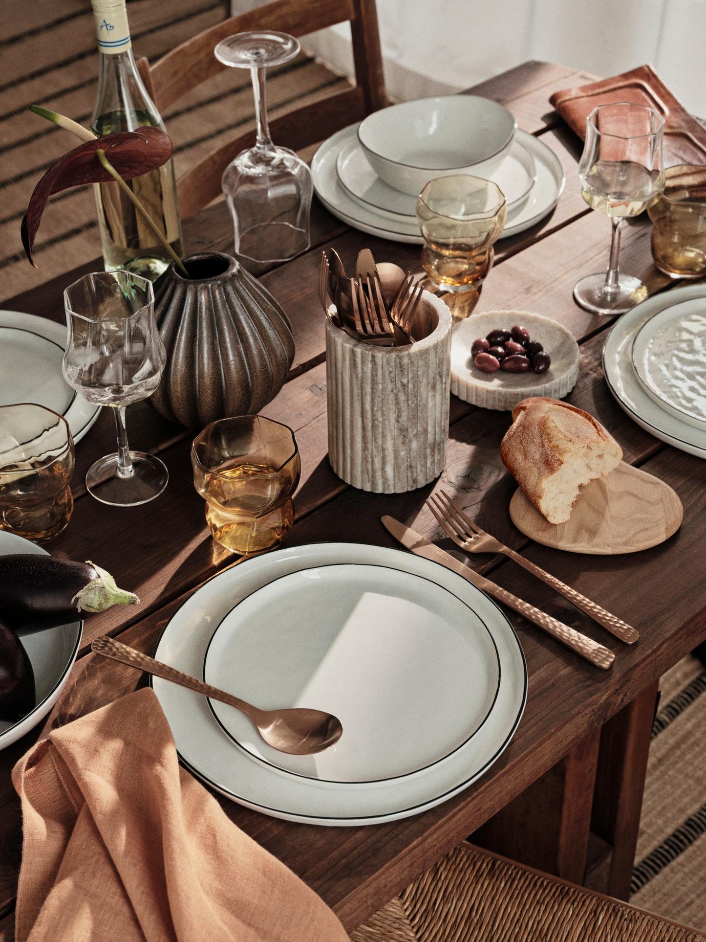 Dining table set with plates, glasses, and cutlery on a wooden table.