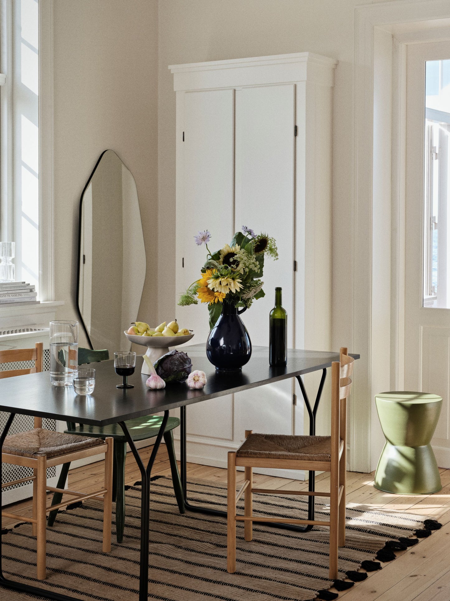 Dining room with a black table, wooden chairs, and a vase of flowers.