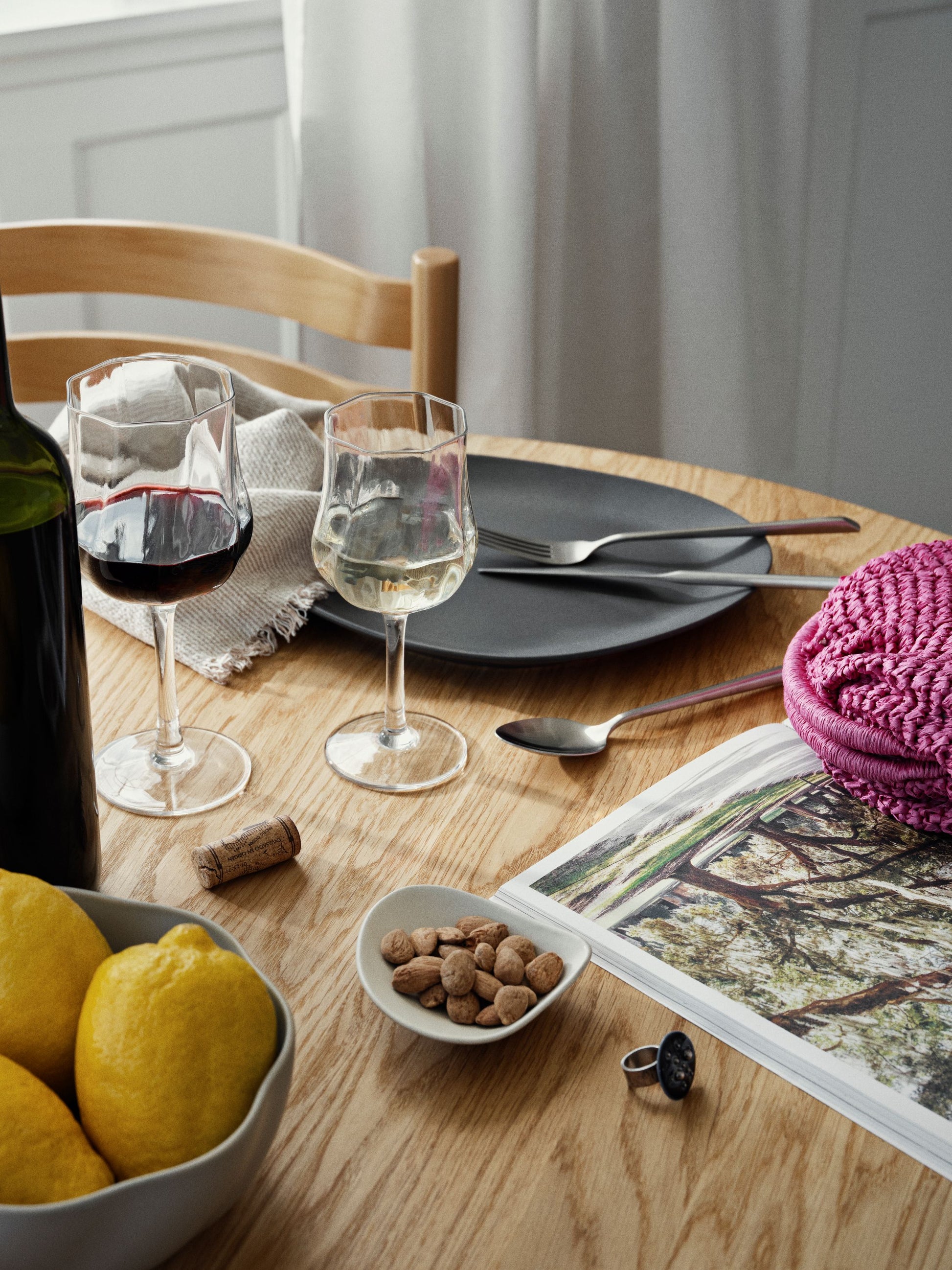 Dining table setting with wine glasses, plates, and a magazine.