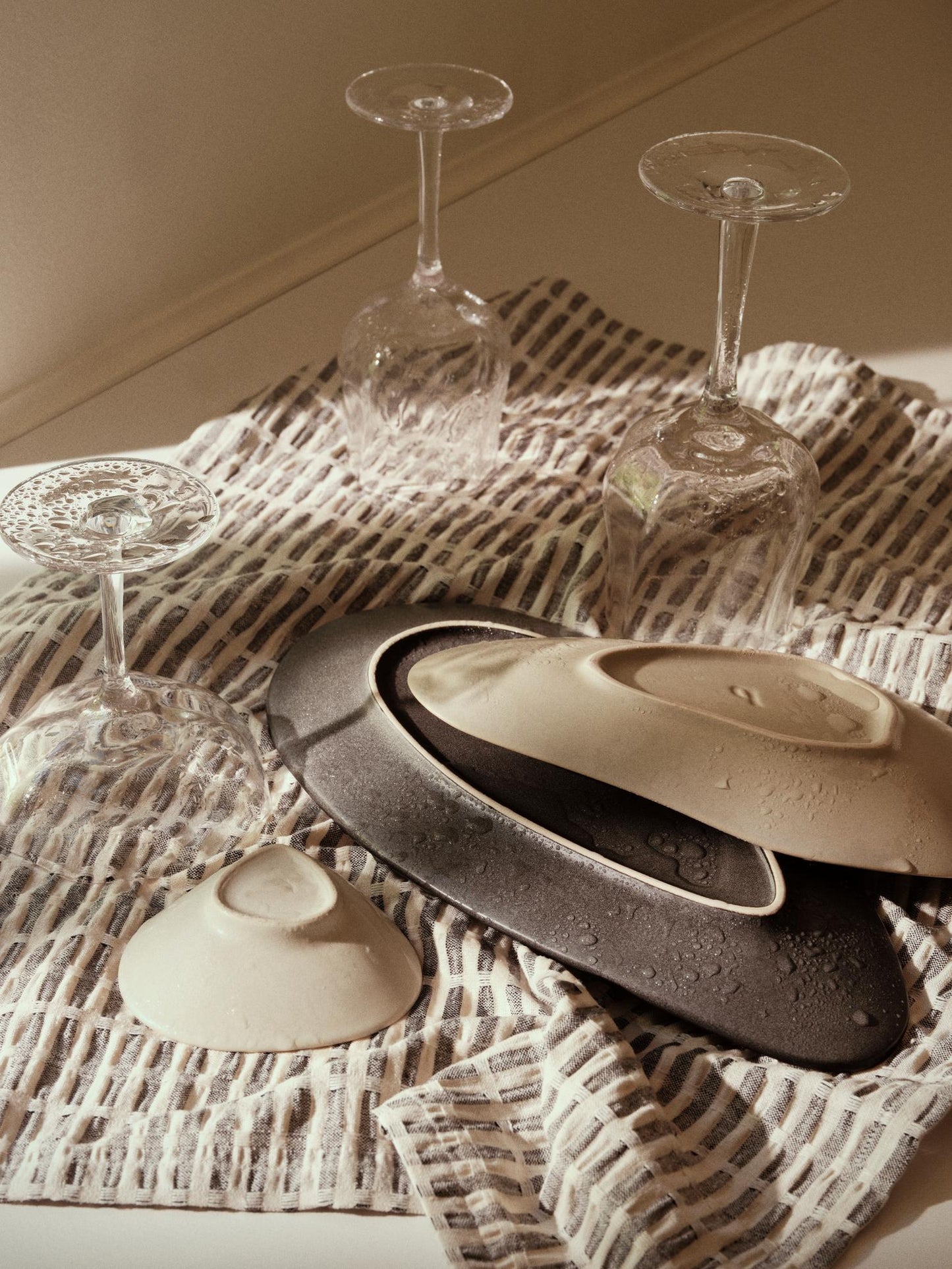 Ceramic lids on a textured surface with glassware in the background