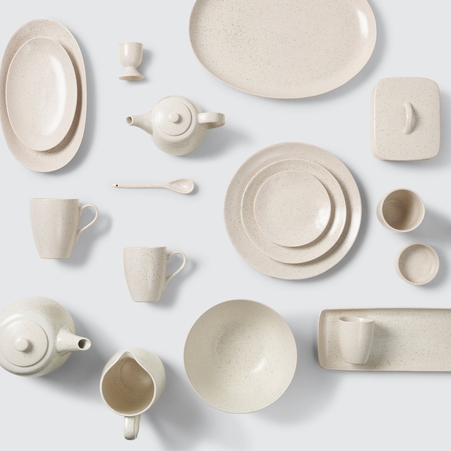Collection of beige ceramic tableware on a light gray background