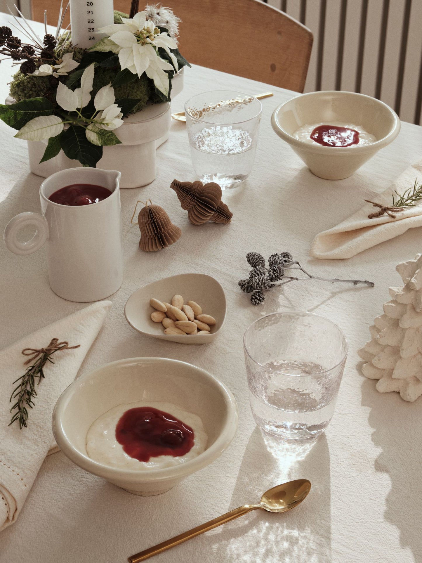 Dining table setting with bowls, cups, and decorative elements on a white tablecloth.