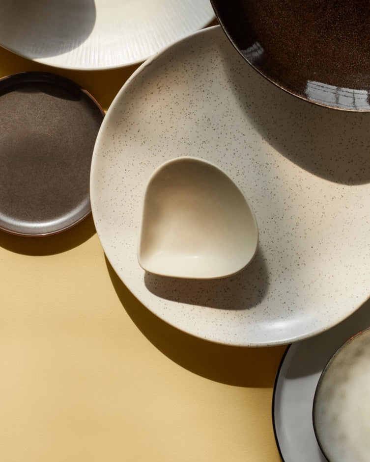 Collection of ceramic plates and bowls on a beige surface