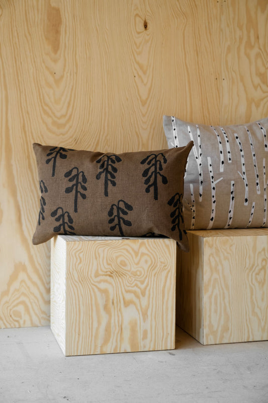 Two patterned pillows on wooden blocks against a wooden wall.
