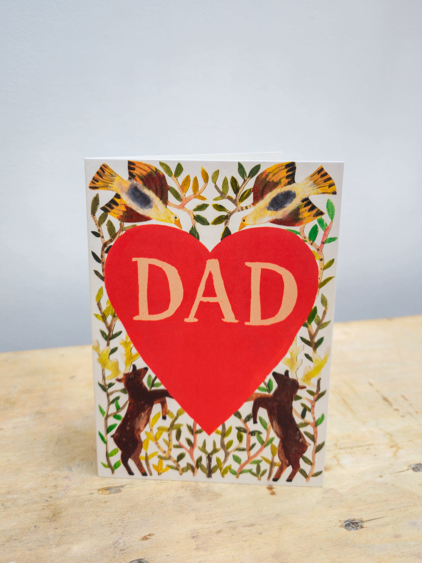 Greeting card with a big red heart and dad written inside, surrounded by vines, 2 stags and 2 birds.