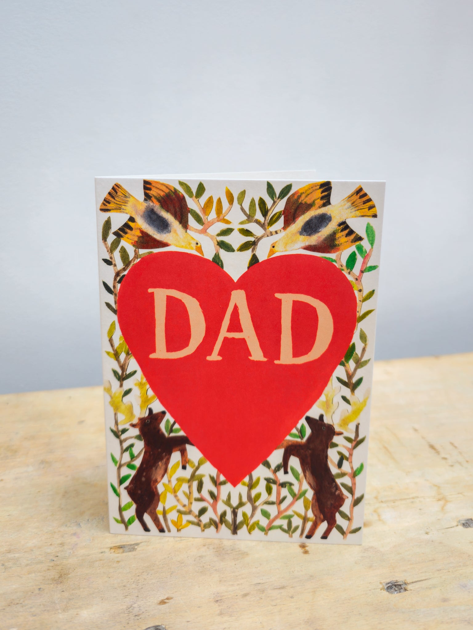 Greeting card with a big red heart and dad written inside, surrounded by vines, 2 stags and 2 birds.