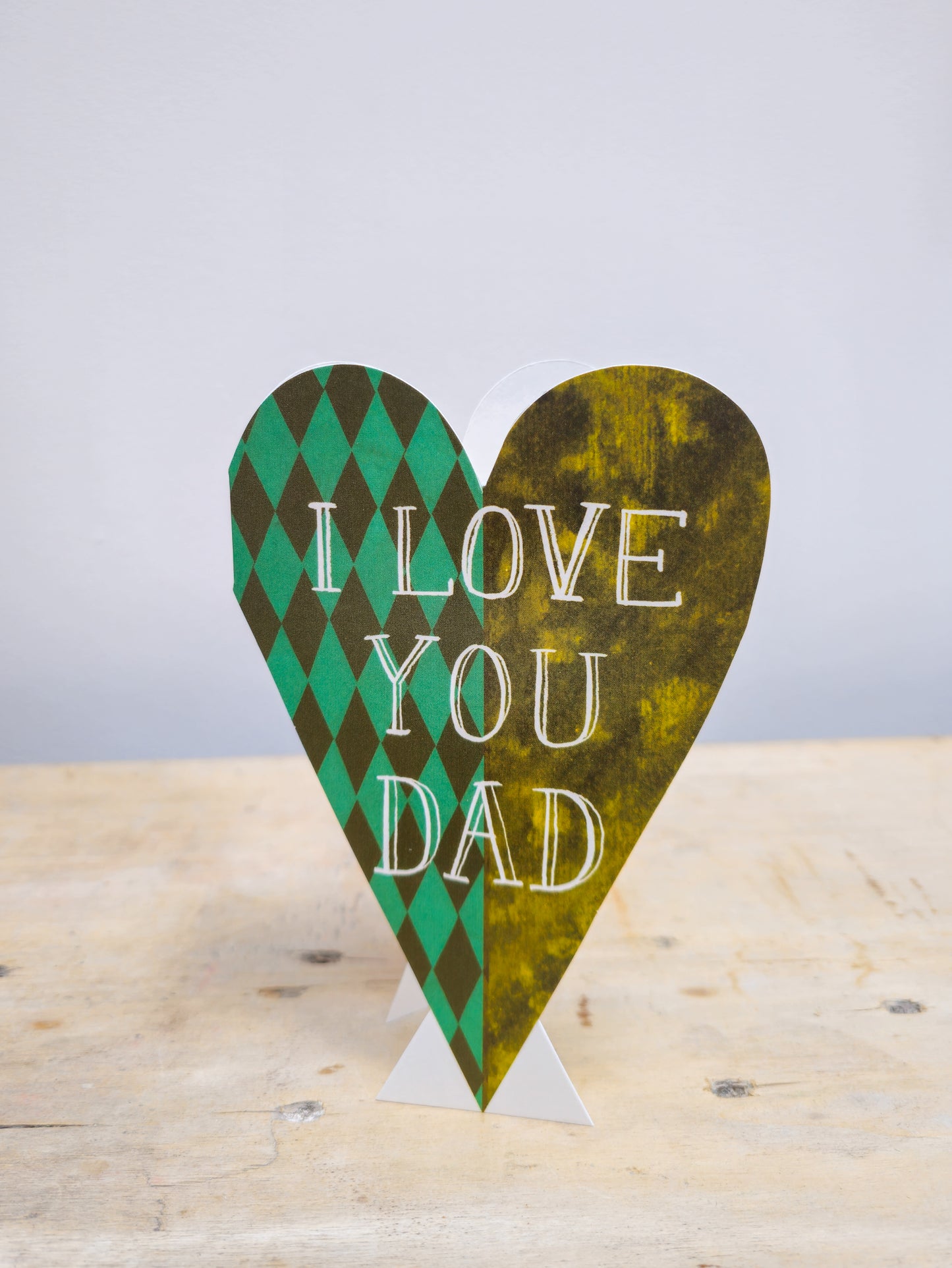 Heart-shaped sign with 'I Love You Dad' text on a wooden surface