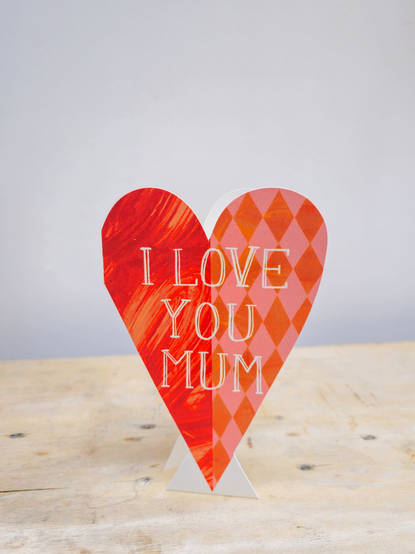 Heart-shaped sign with 'I LOVE YOU MUM' text on a wooden surface