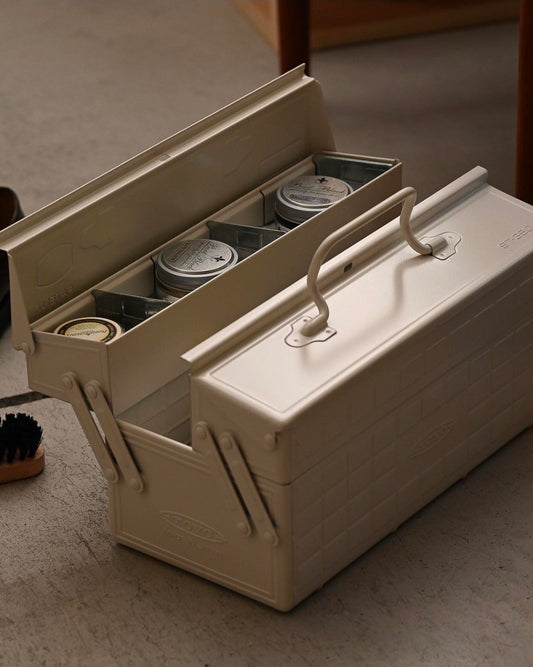 Beige toolbox with compartments on a concrete floor