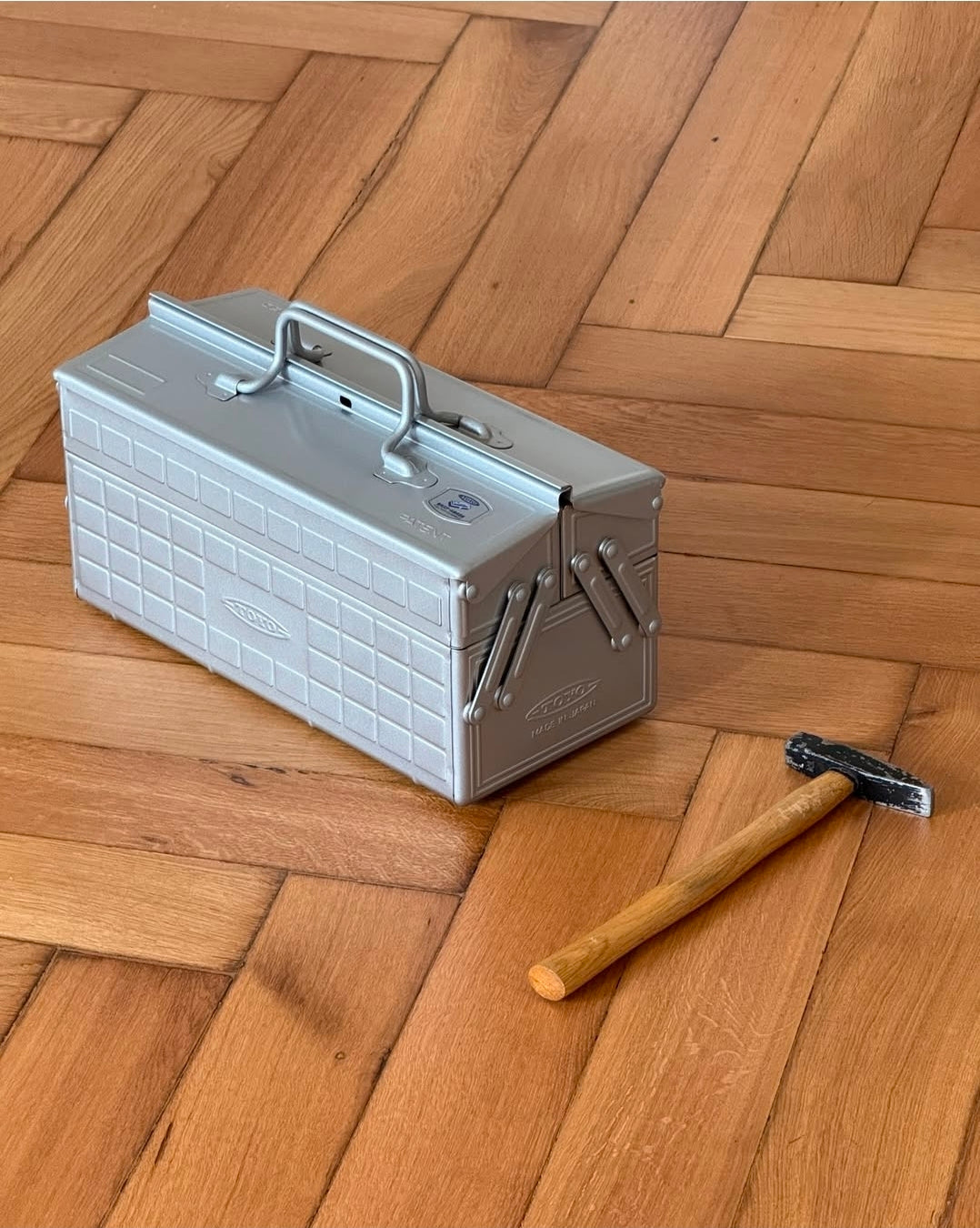 Metal toolbox and hammer on a wooden floor