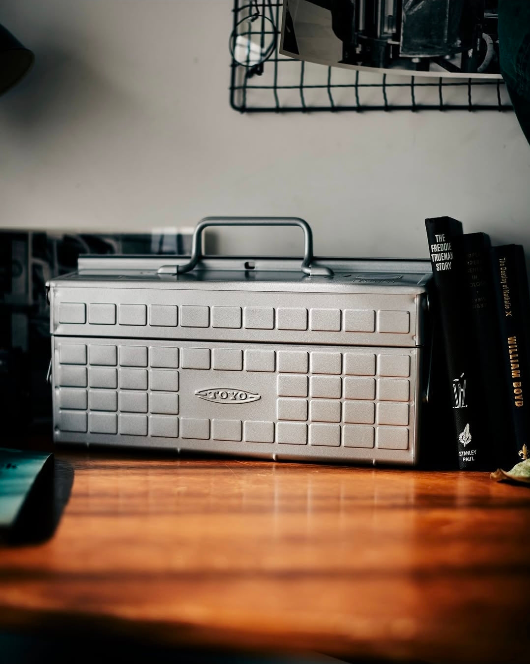 Silver toolbox on a wooden surface with books in the background