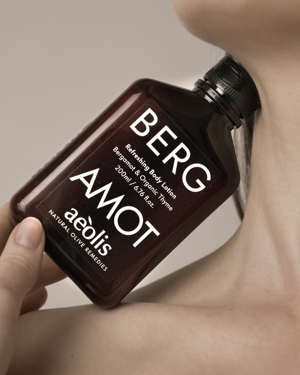 Aeolis bergamot body lotion held against the neck