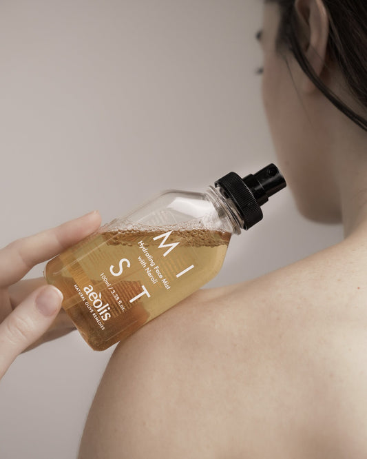 Aeolis face and body mist held against a bare shoulder