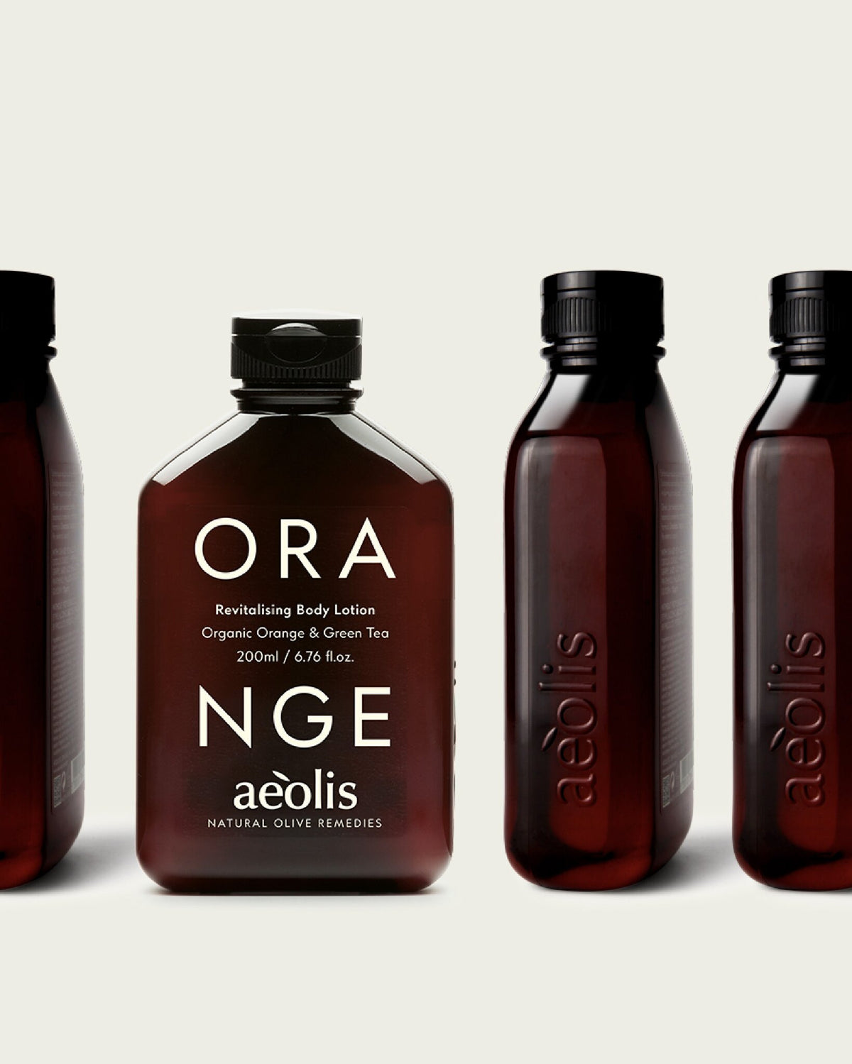 Aeolis orange and green tea body lotion beside other amber bottles