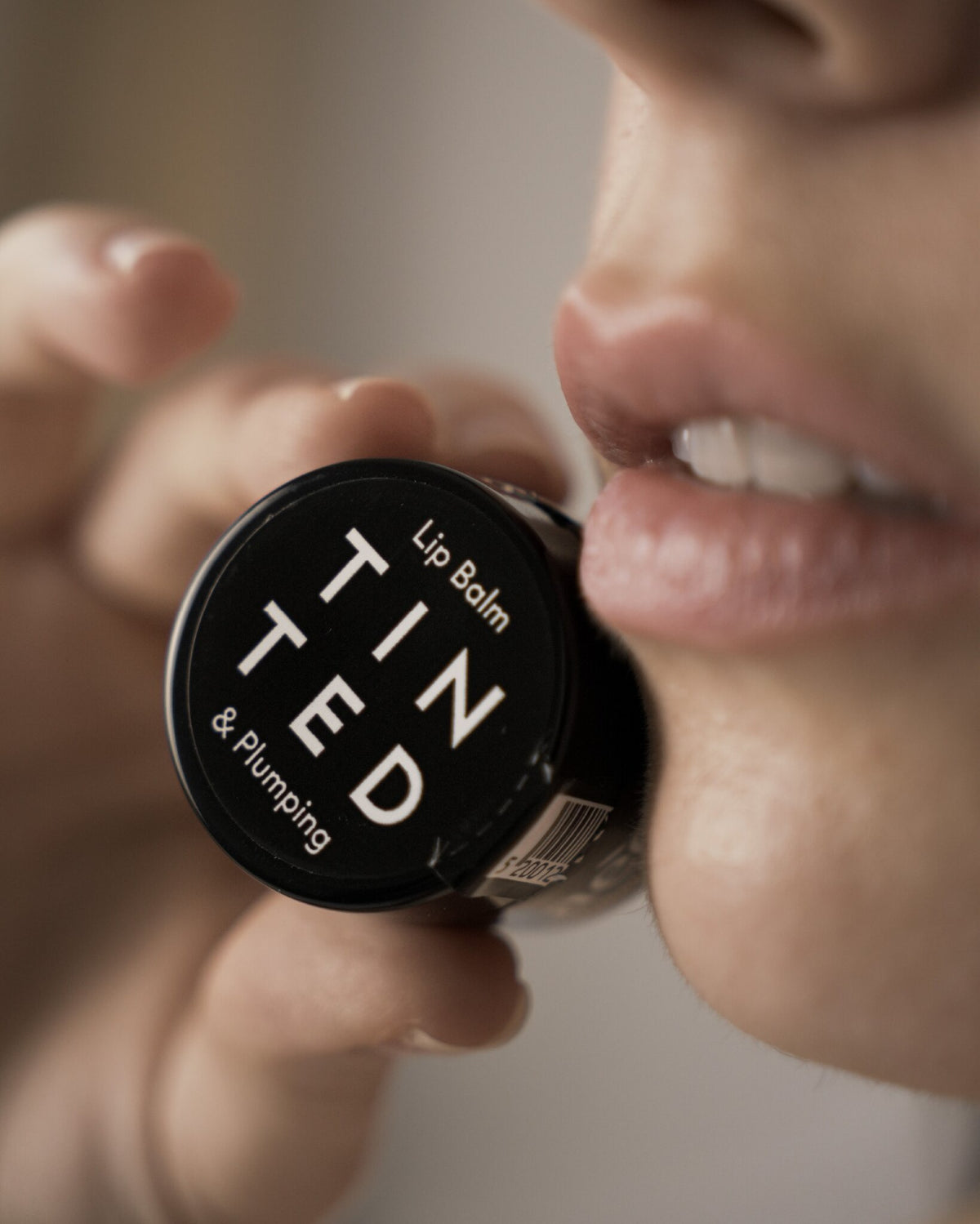 Aeolis tinted lip balm jar held up to the lips