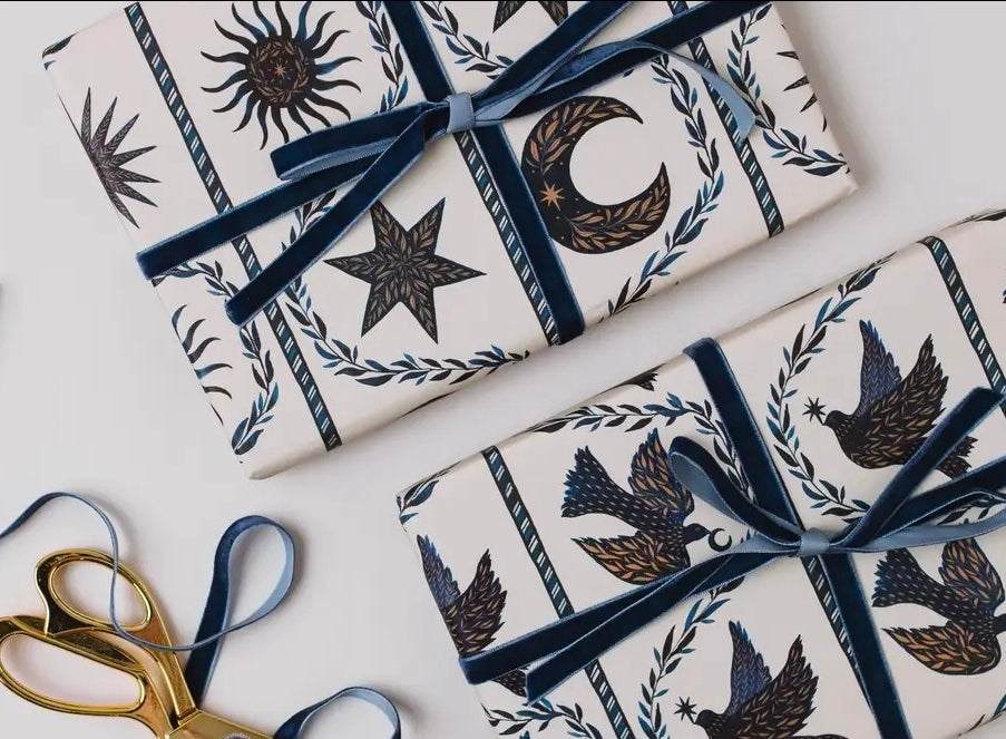 Presents wrapped in celestial moon and star paper tied with navy velvet ribbon