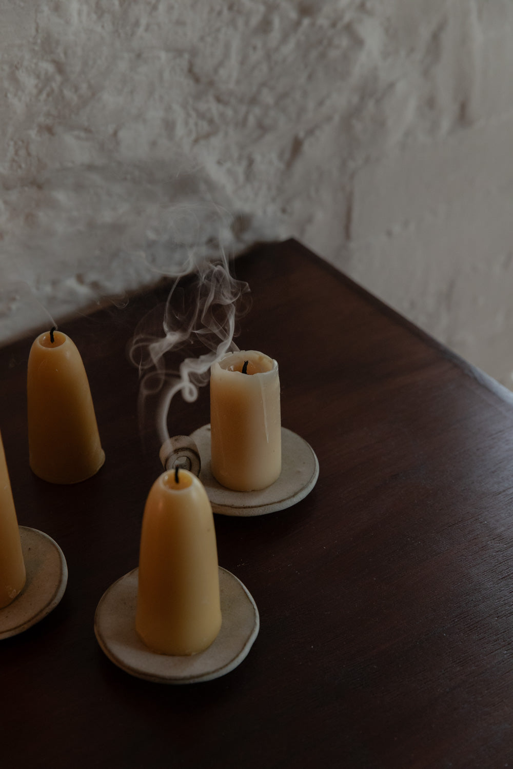 Smoke rising from freshly snuffed beeswax candles on ceramic candle plates