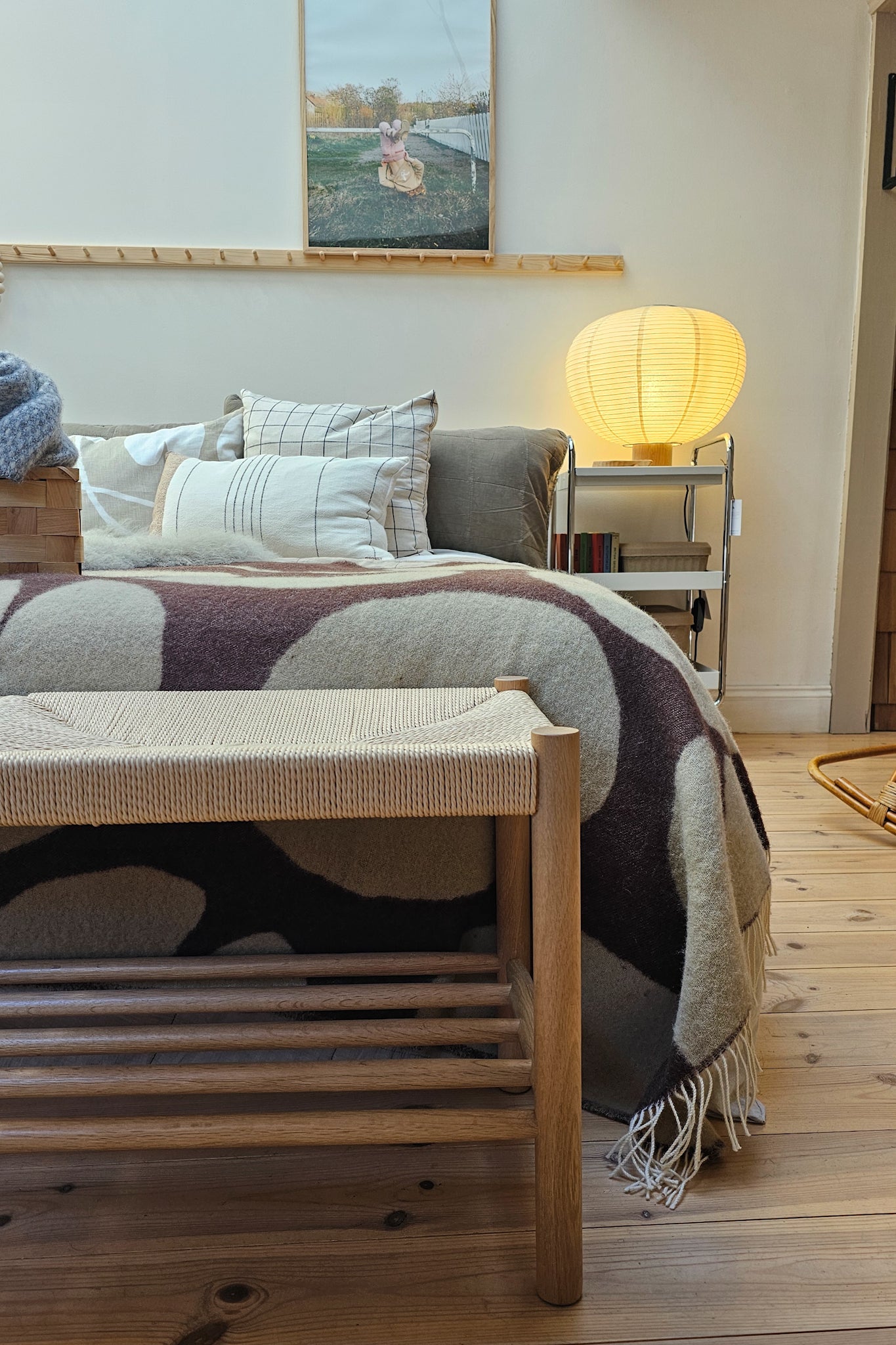 Longworth Bench in bedroom setting with brass floor lamp, pine floorboards and layered linen bedding