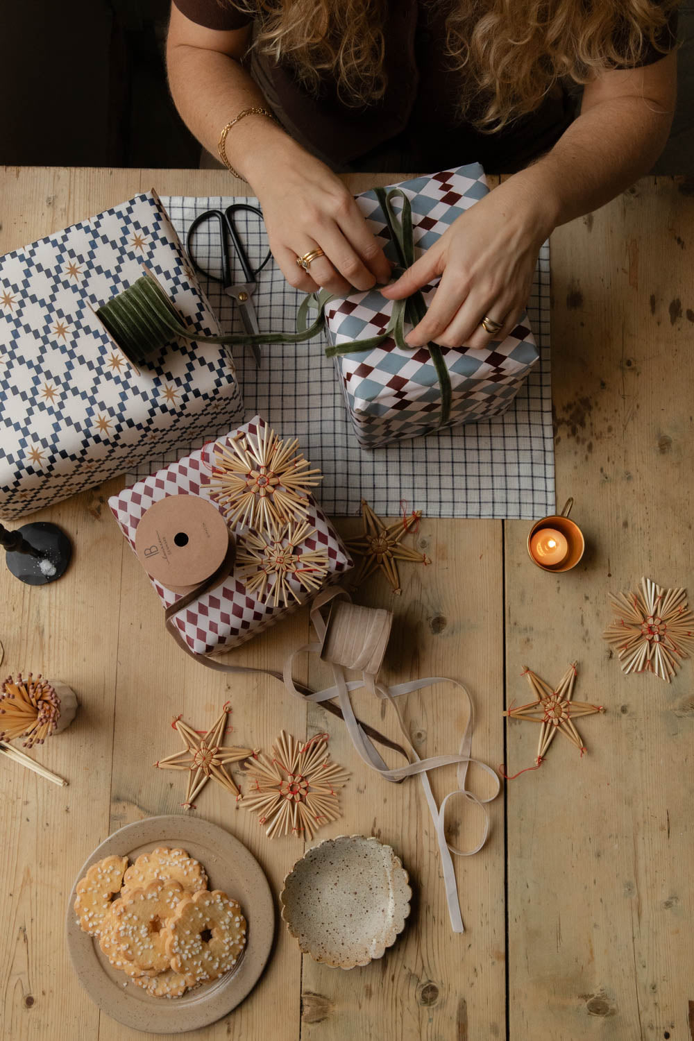 Hands tying velvet ribbon around a present wrapped in gingham paper