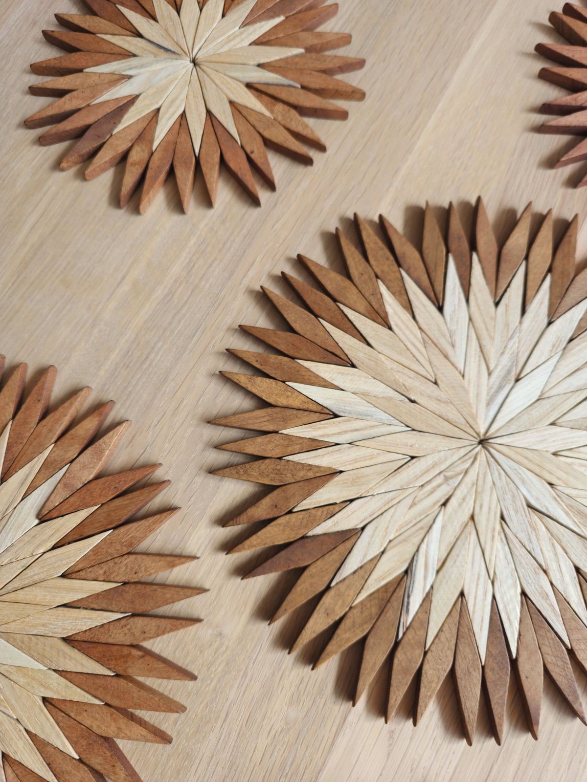 Close-up of handmade two-tone wooden starburst trivets showing the hand-assembled pale and brown beechwood pieces