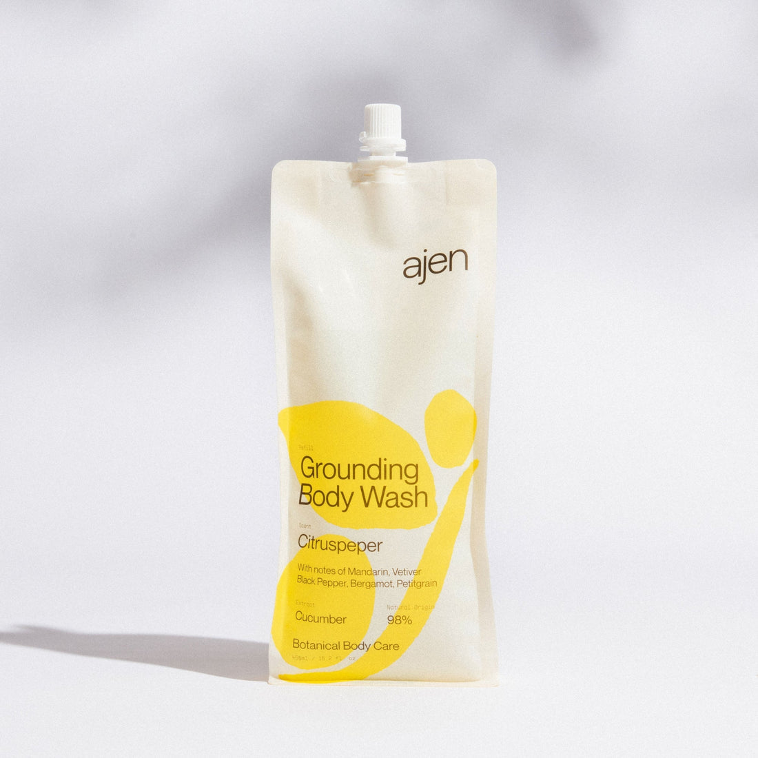 Ajen Grounding Citruspeper Body Wash packaging with yellow abstract design on a gray background.