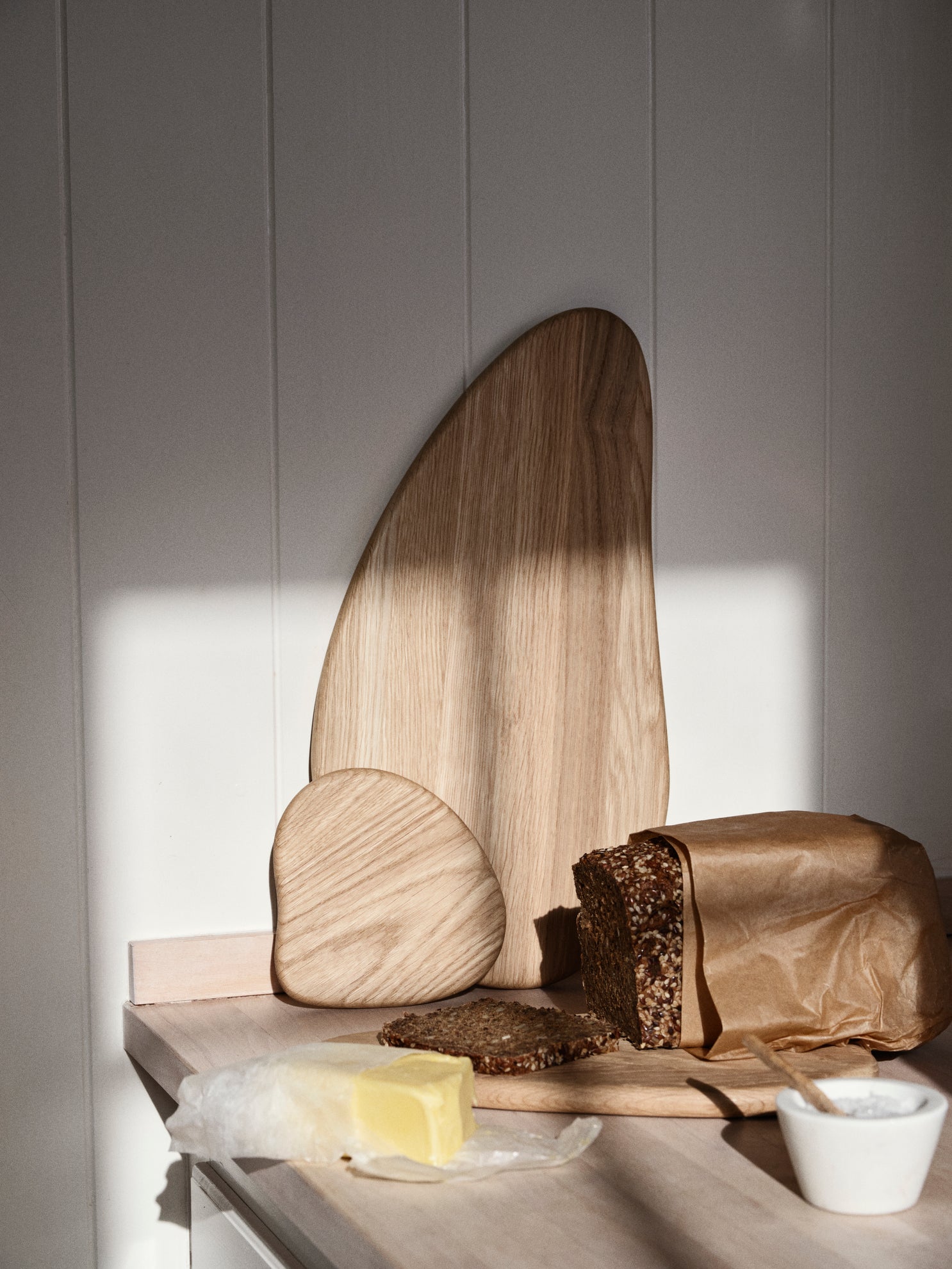 Wooden cutting board with bread and butter on a neutral background