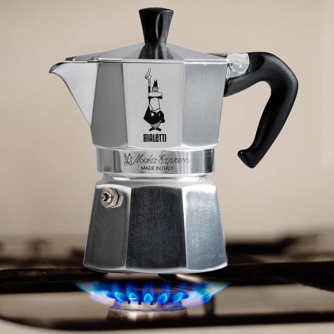 Bialetti Moka Express coffee maker on a stove with a blurred background