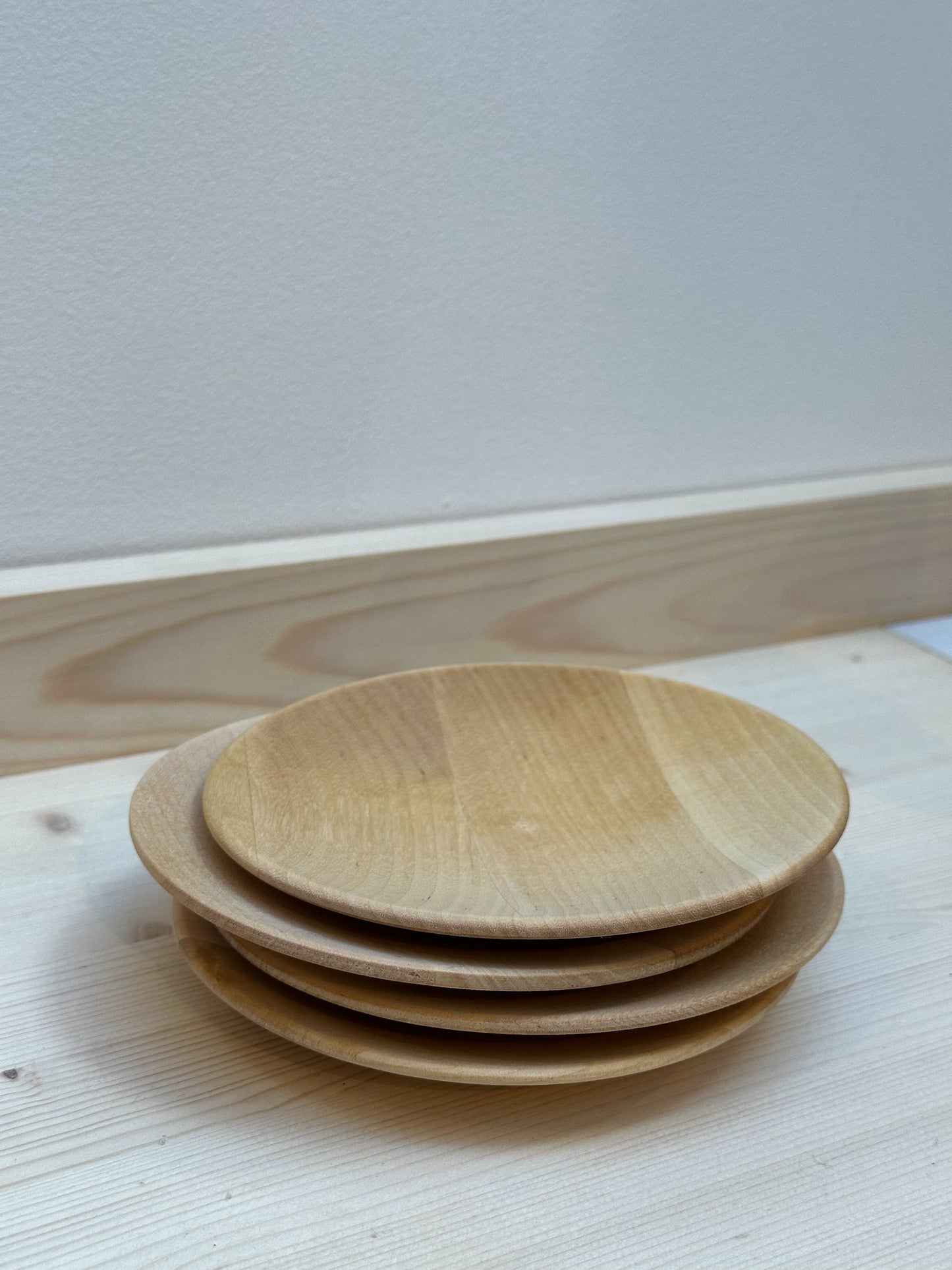 A set of four birch wood plates stacked on top of each other against a white background.