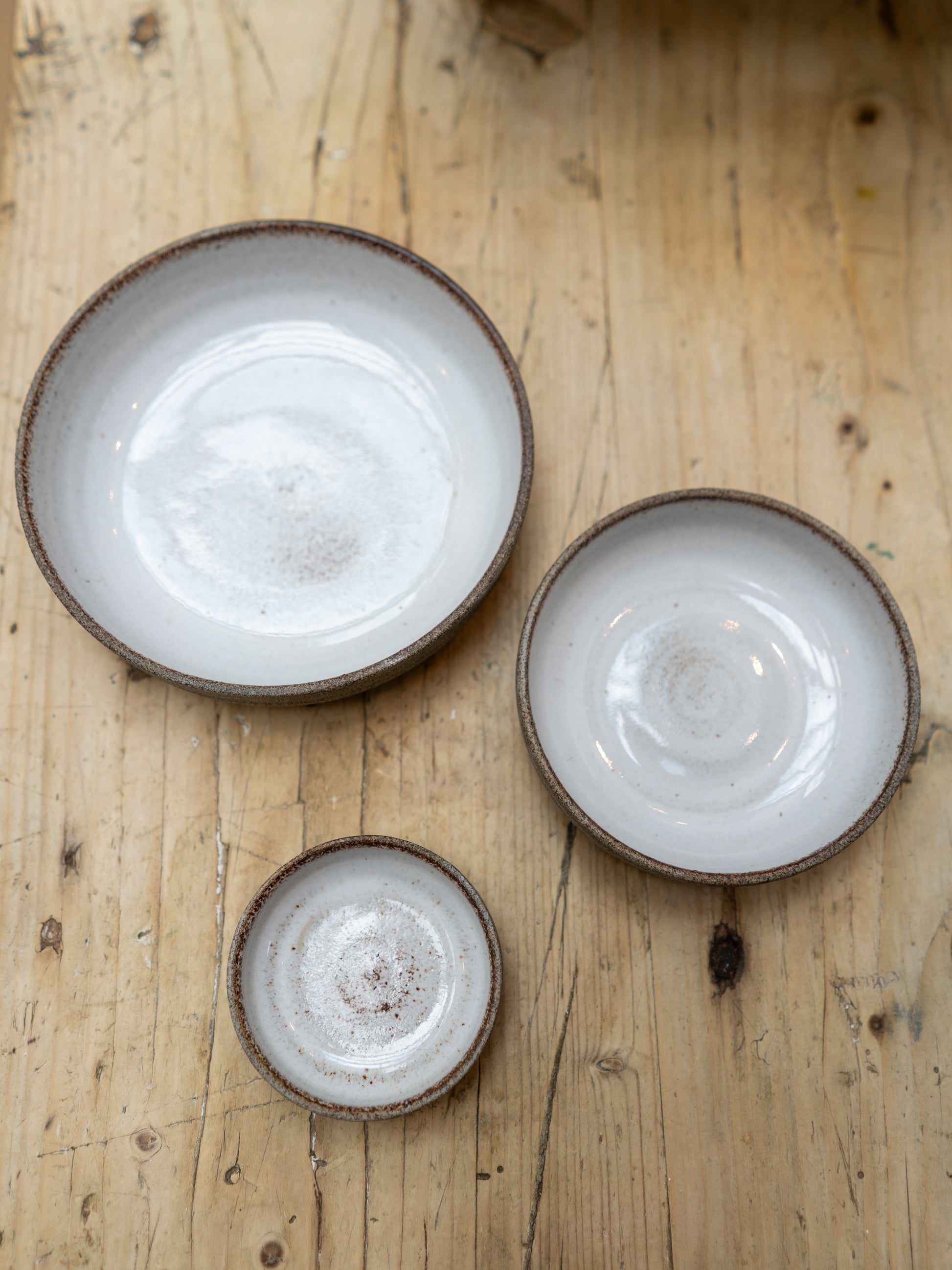 Three ceramic plates of different sizes on a wooden surface