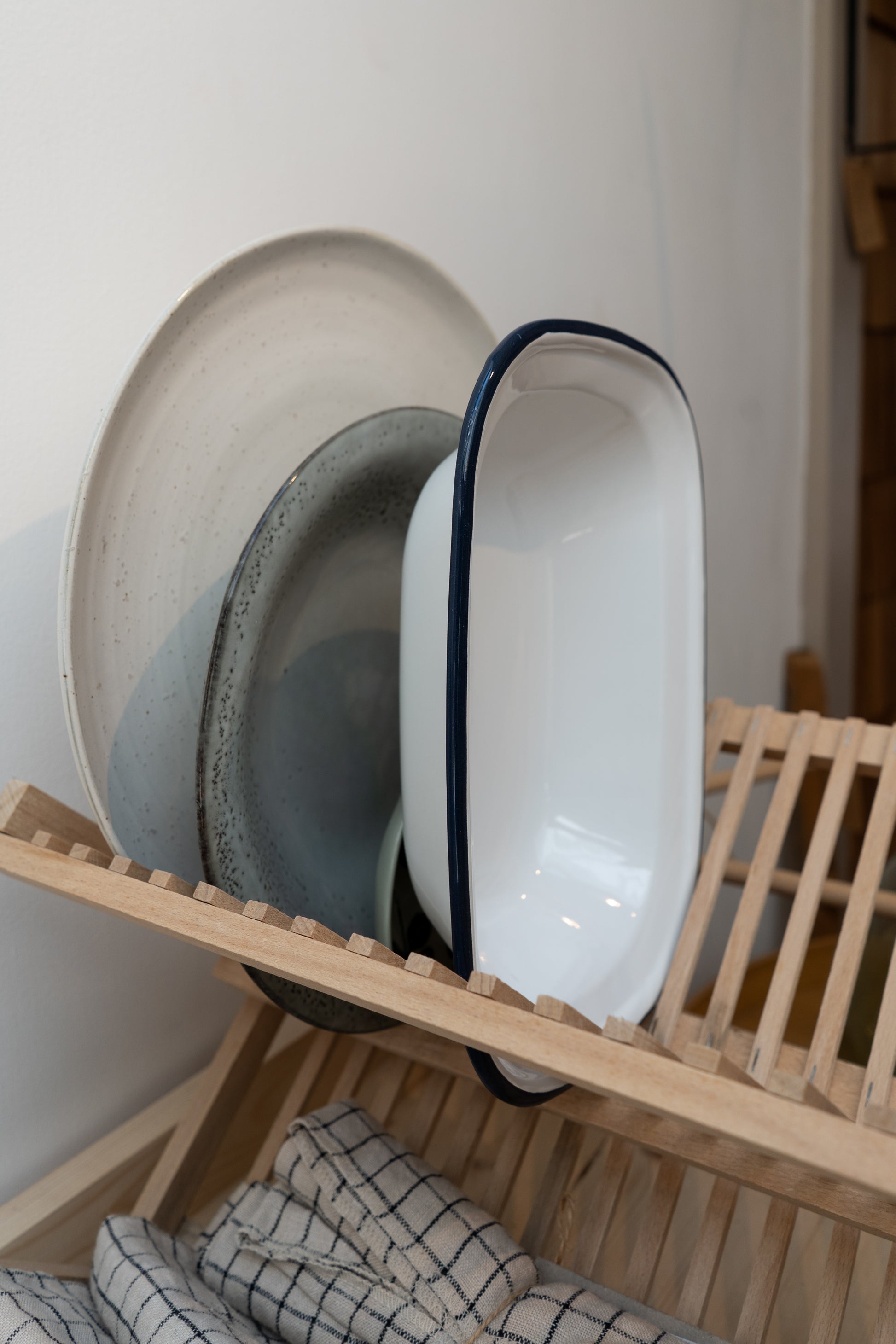 Dish rack with plates and bowls on a white wall background