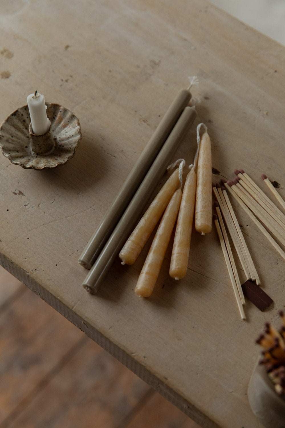 Candle sticks, matches, and a candle holder on a wooden surface.