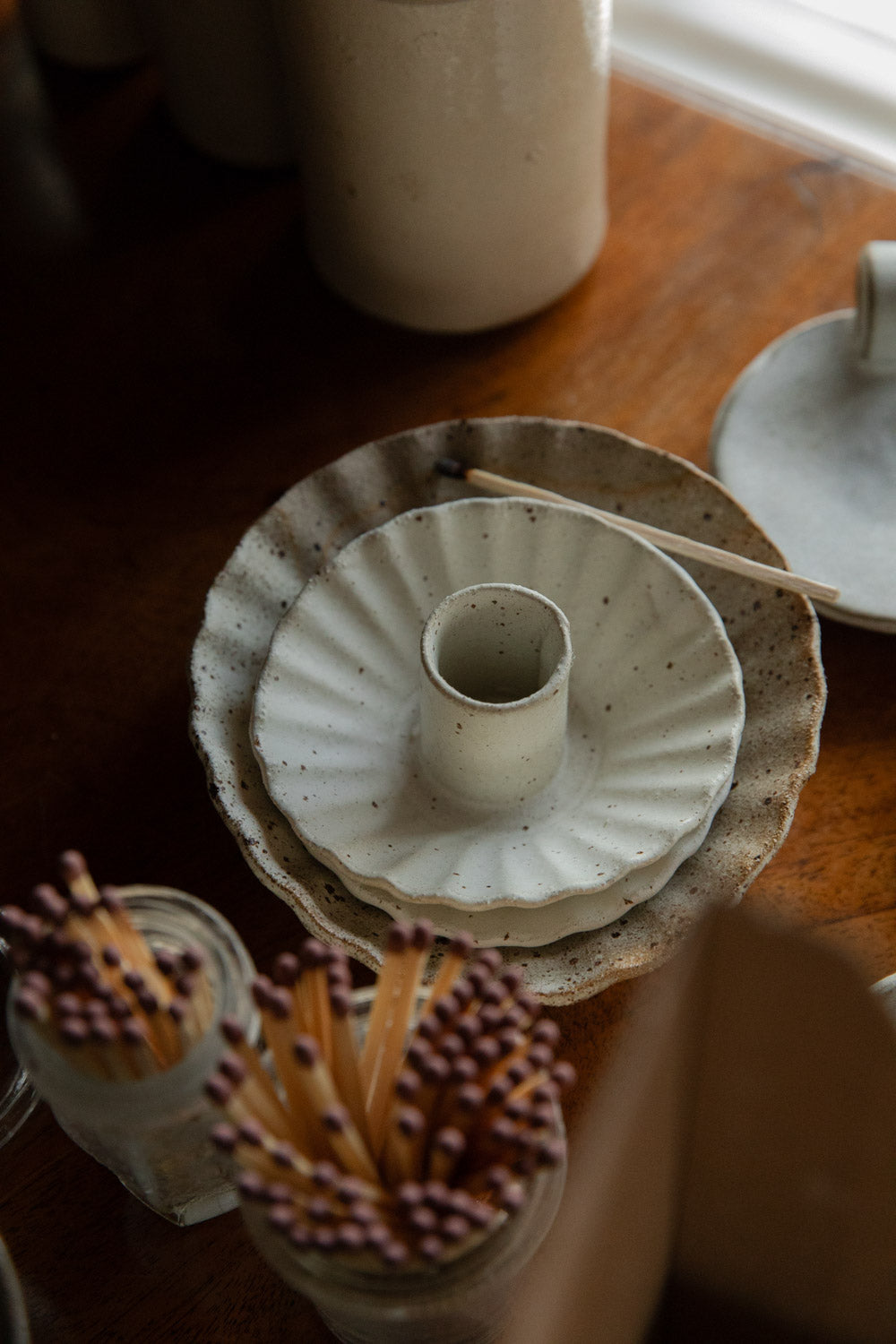Handmade white ceramic holder next to pots of matches.