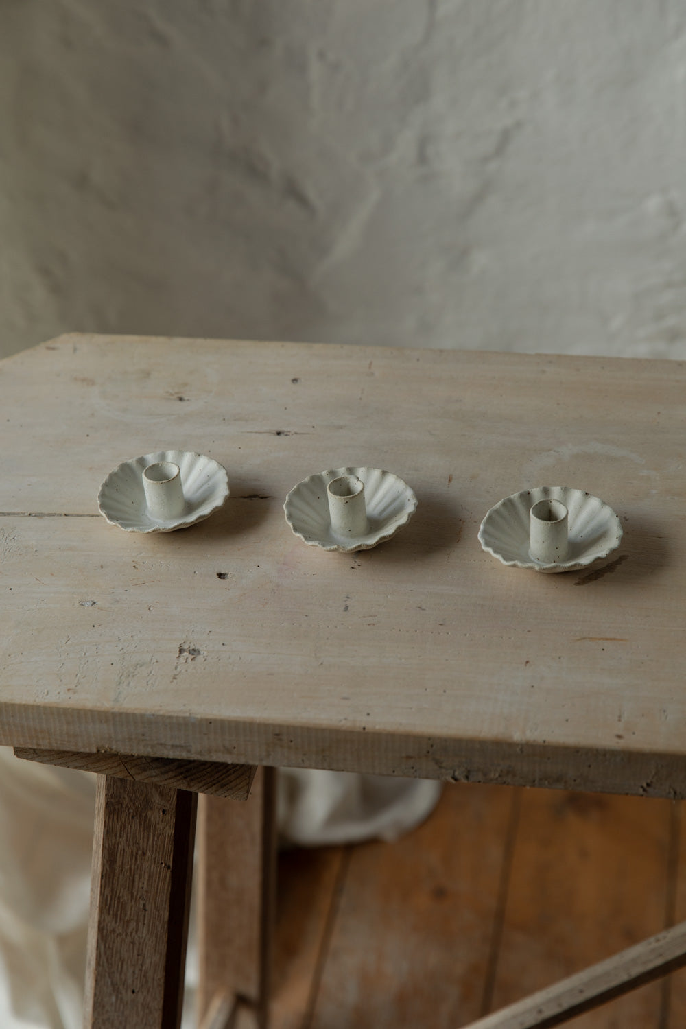 Three small ceramic candle holders on a wooden surface with a neutral background.