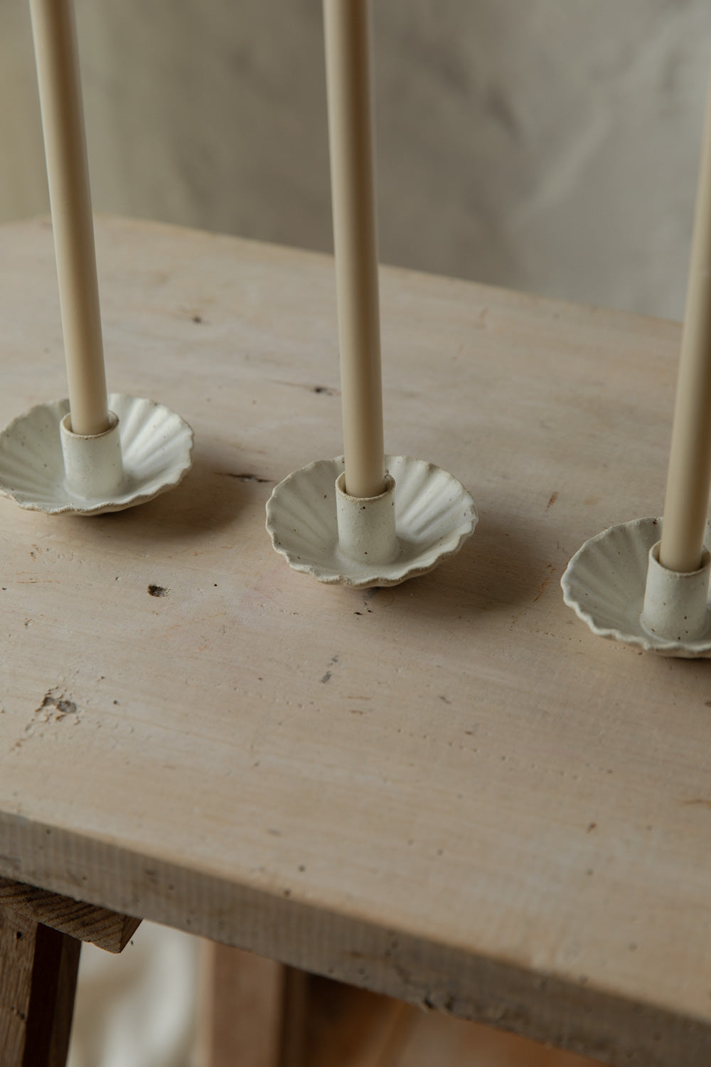 Three candle holders with candles on a wooden surface.