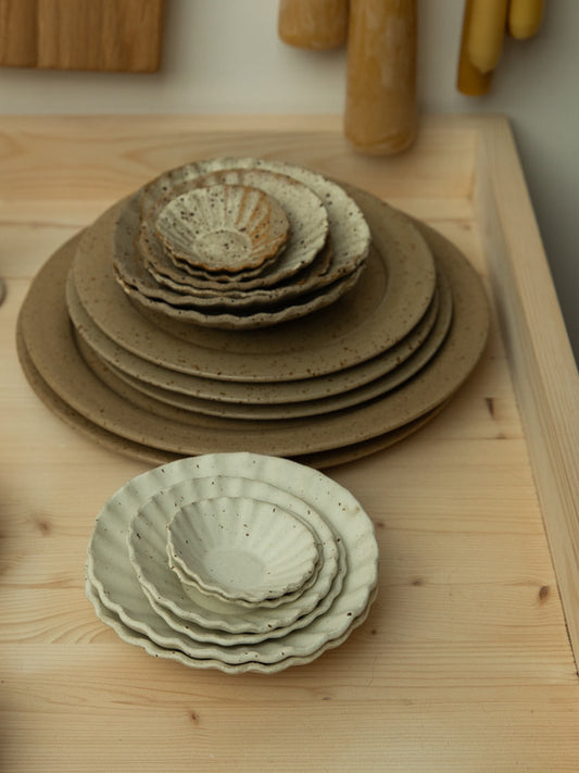 Stack of ceramic bowls and plates on a wooden surface.