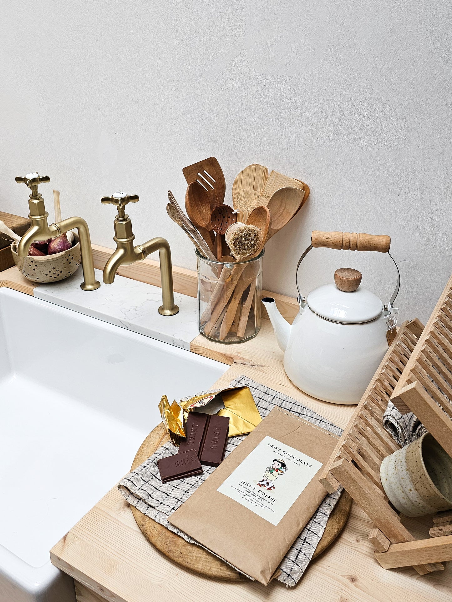 Kitchen counter with wooden utensils, teapot, and chocolate on a white background