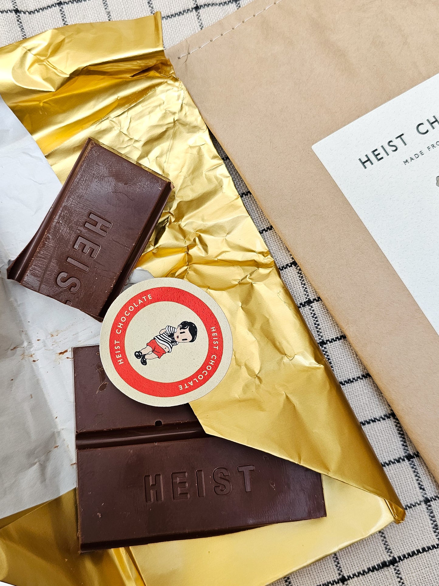 Chocolate bars with gold foil and a 'Heist' label on a checkered surface