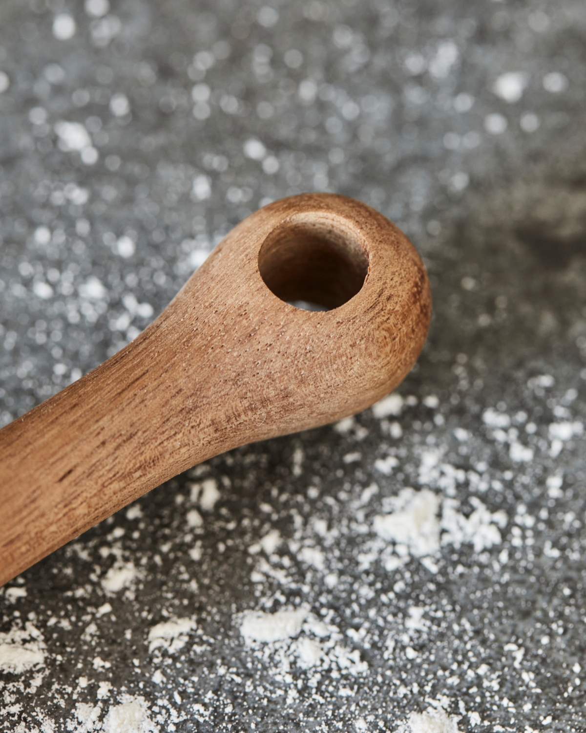 Wooden rolling pin handle on a surface with flour